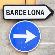 A street sign reading "Barcelona" over a blue direction arrow